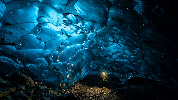 Small group exploring magical ice cave chambers with professional guide