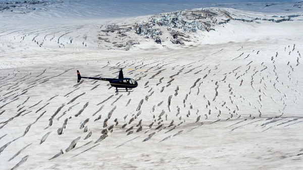 Helicopter landed on pristine glacier with passengers exploring ice formations